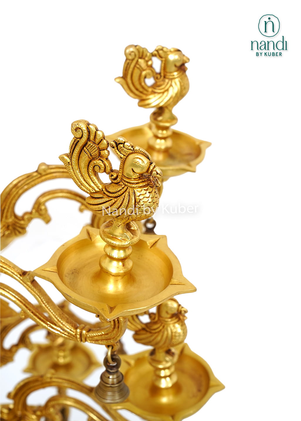 Large handcrafted brass Deepam with multiple oil lamp tiers, peacock motifs, floral detailing, and hanging bells for temples and pooja spaces.