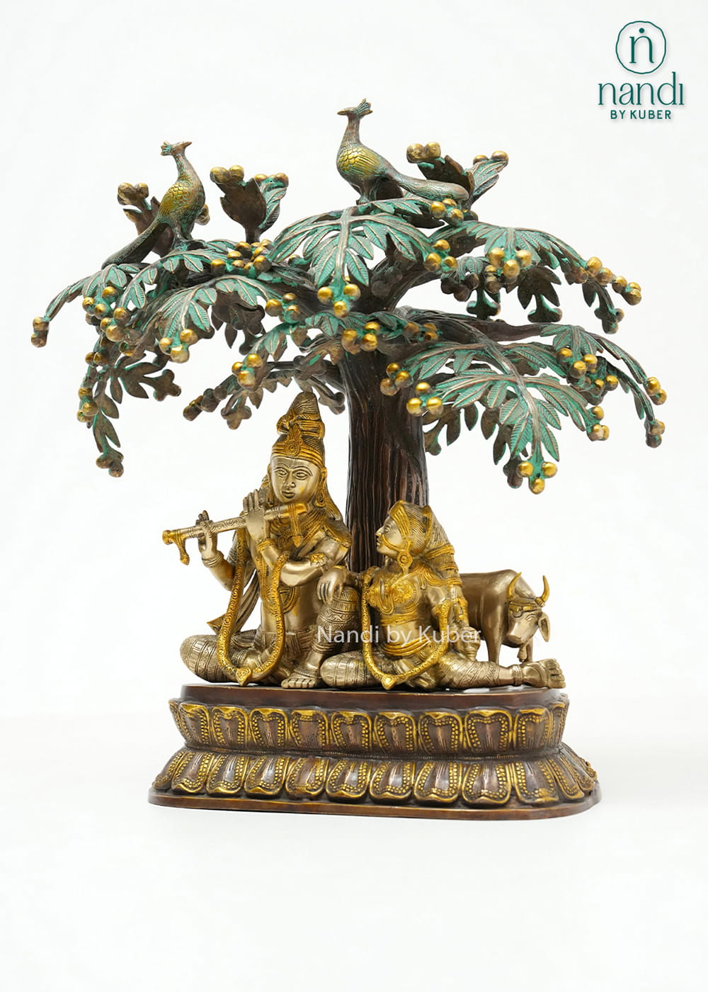 Decorative three-tone brass Radha Krishna statue beneath an ornate tree with peacocks, symbolizing love, devotion, and harmony.