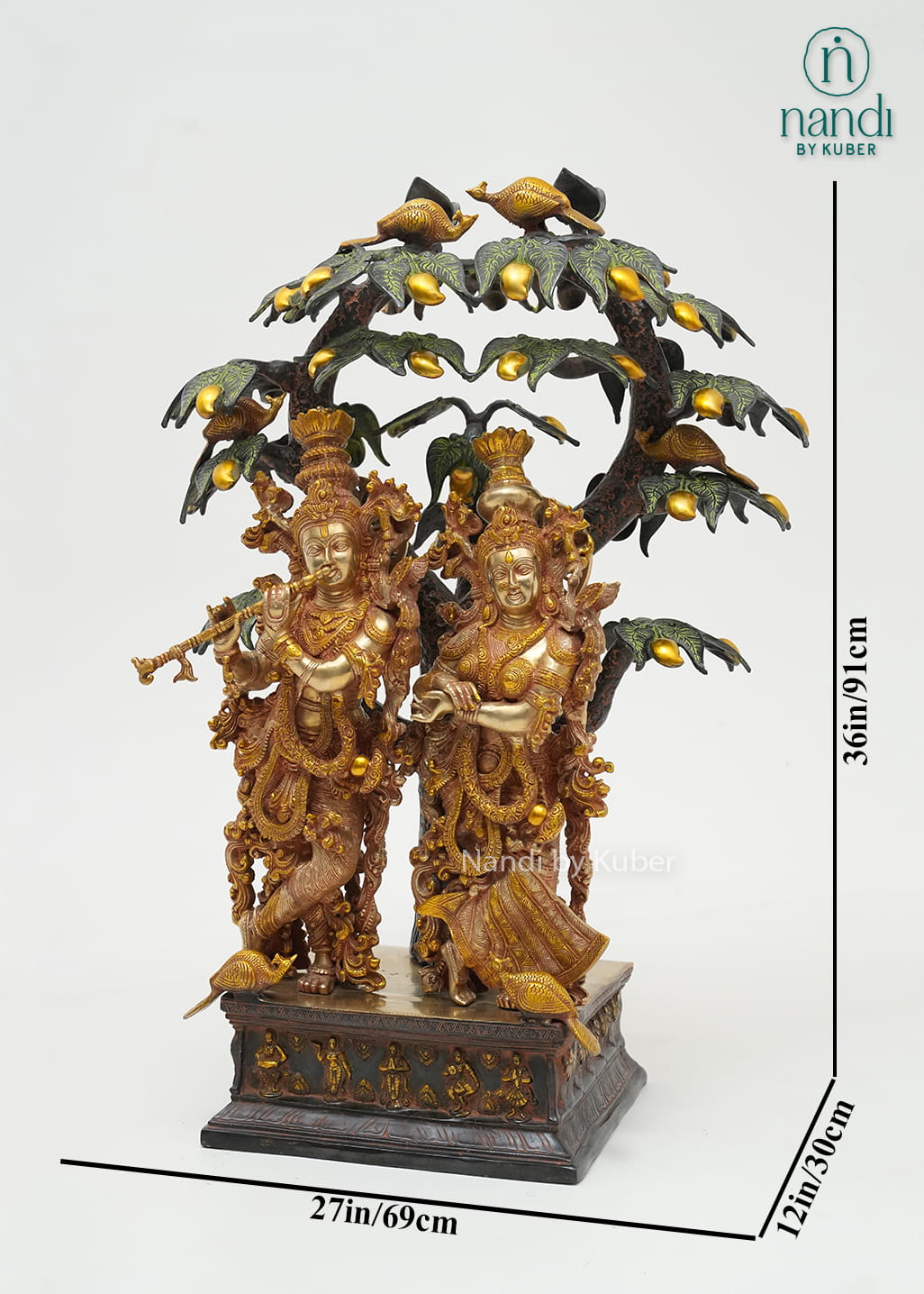 Decorative brass Radha Krishna sculpture beneath an intricately detailed tree with birds, symbolizing love, devotion, and harmony.