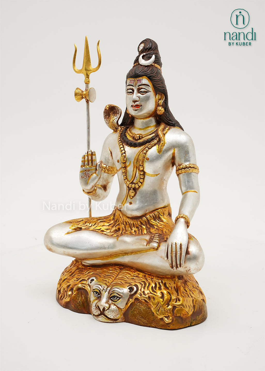Handcrafted silver and gold finish Lord Shiva meditation statue with trident and sacred serpent, seated on an ornate tiger-inspired base, ideal for home temples, spiritual décor, yoga spaces, and devotional gifting.