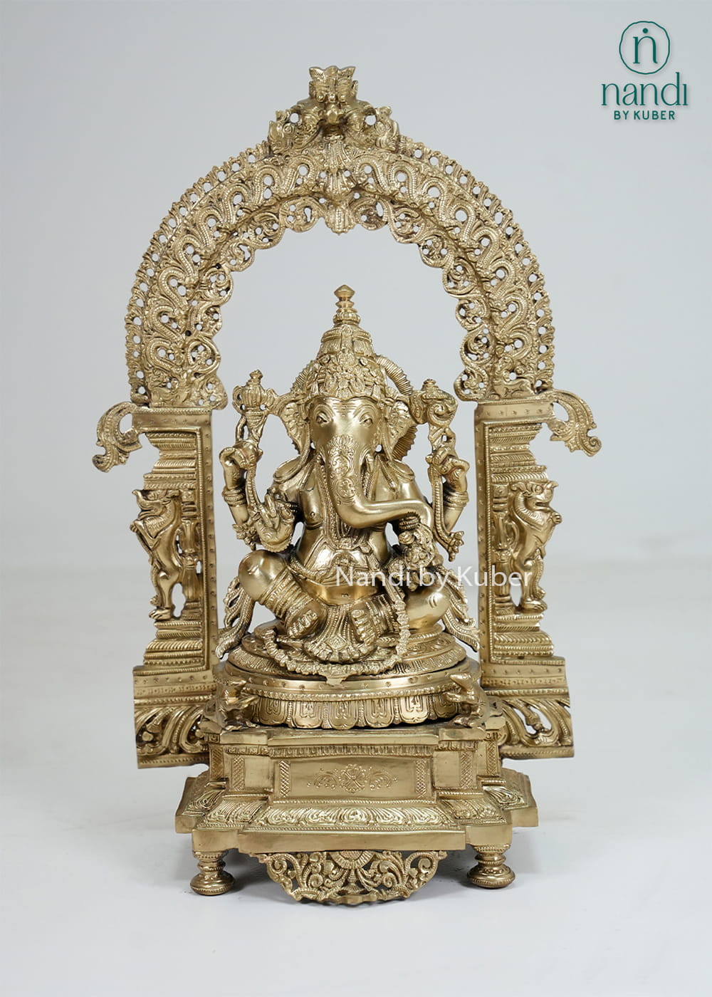 Bronze Ganesha statue with ornate temple arch and carved pedestal