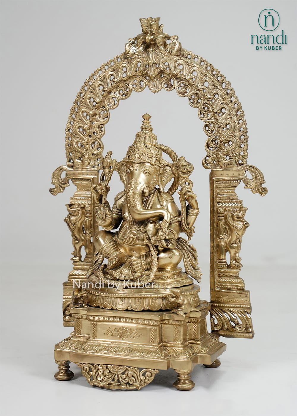 Bronze Ganesha statue with ornate temple arch and carved pedestal