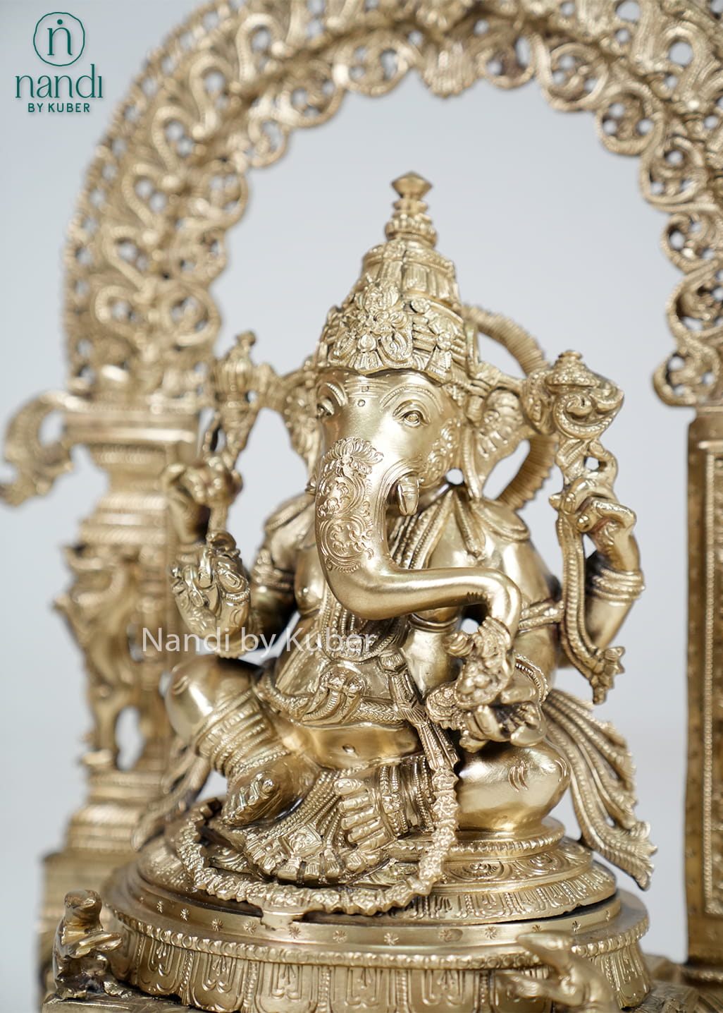 Bronze Ganesha statue with ornate temple arch and carved pedestal
