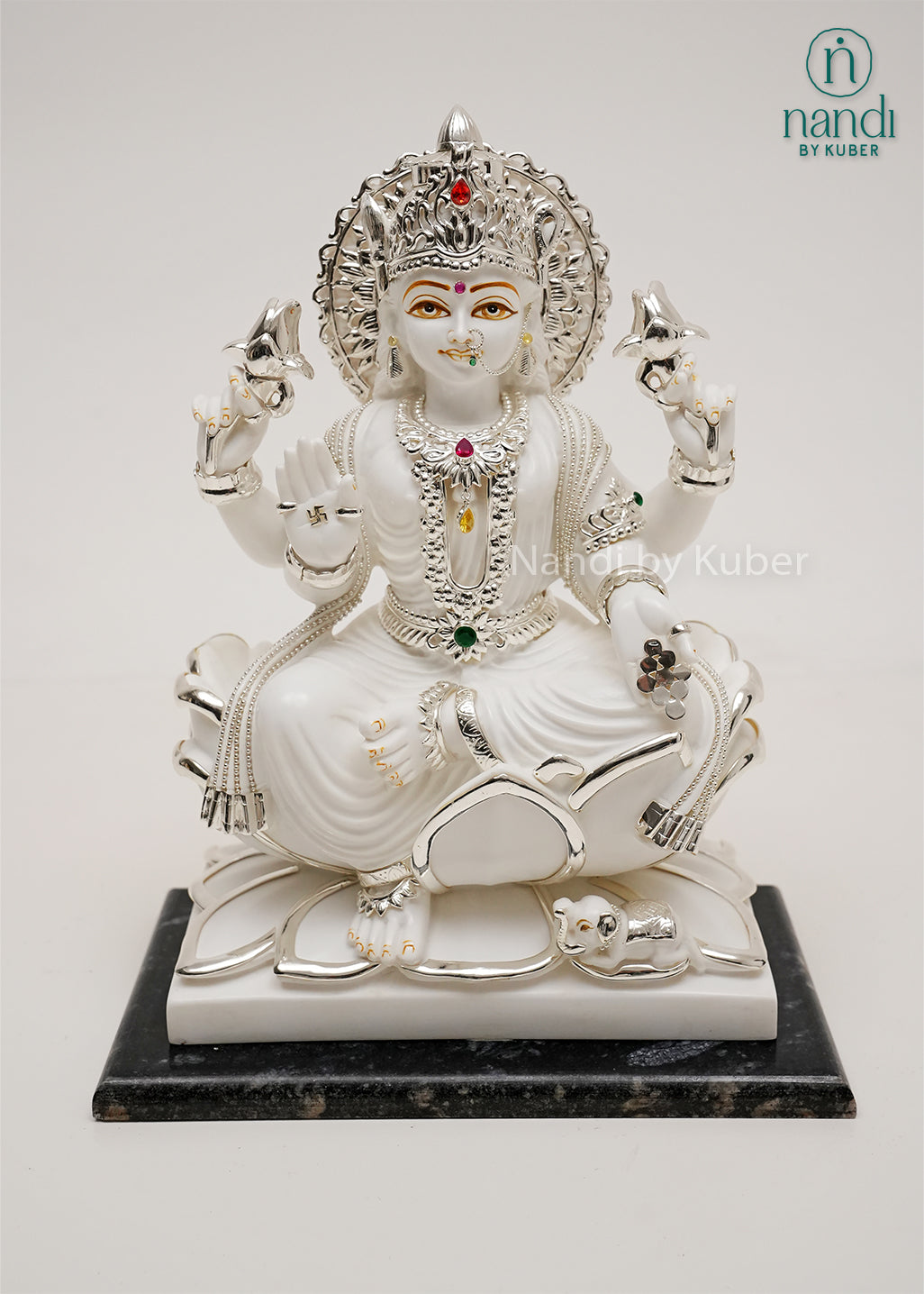 White marble-style Lakshmi sitting on lotus statue with silver detailing, gemstone embellishments, and black base, ideal for home temples, spiritual décor, and prosperity-focused interiors.