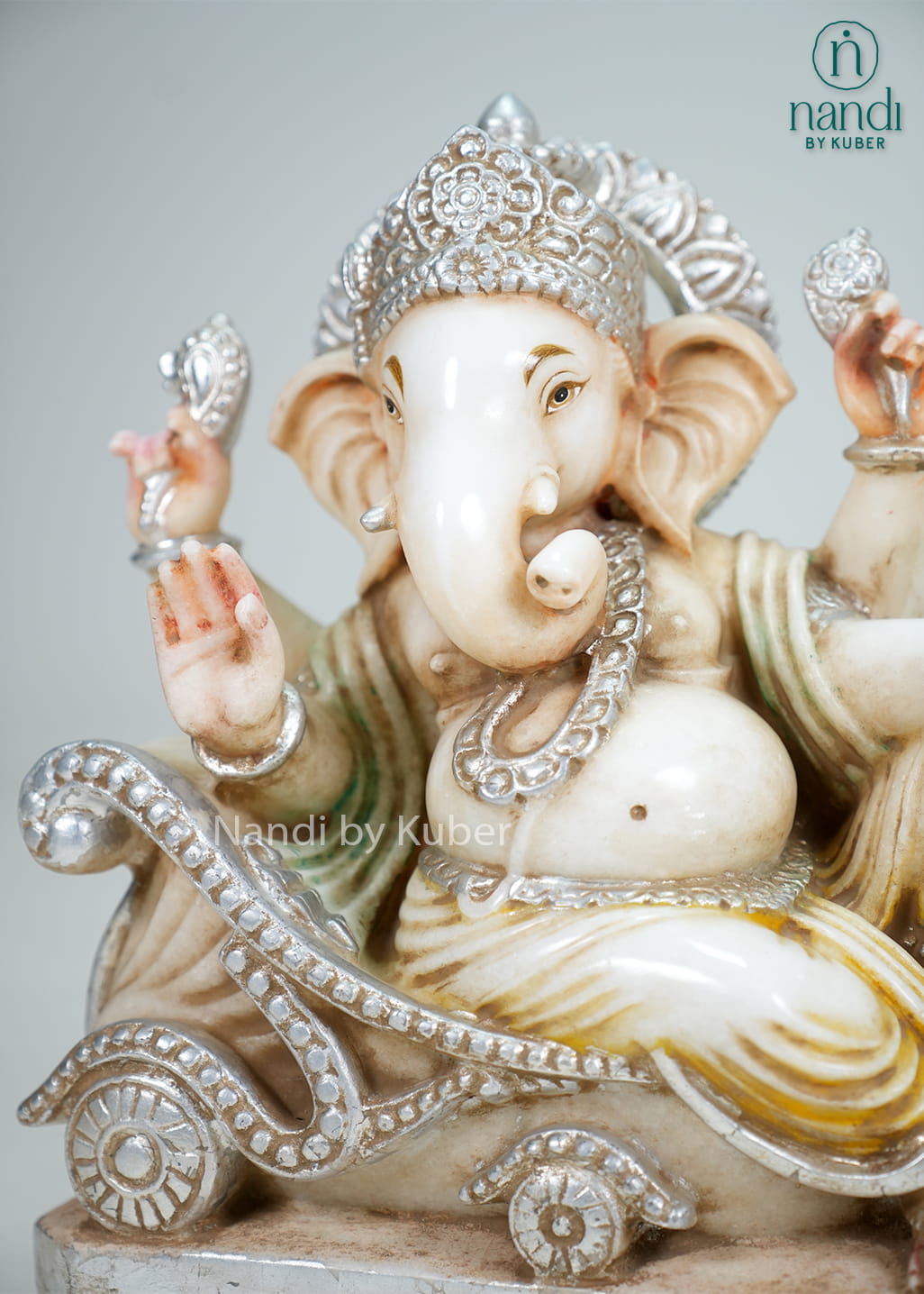 Marble-style Lord Ganesha statue seated on an ornate chariot with sacred mouse companion, intricate detailing, and antique-finish accents.