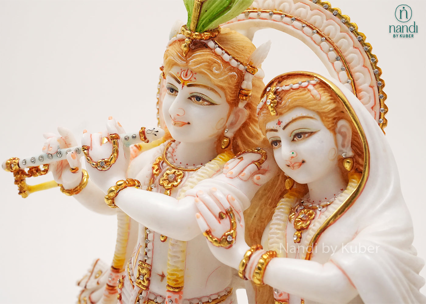 Handcrafted marble Radha Krishna idol with flute-playing Krishna, elegant gold embellishments, and lotus base, ideal for home temples, spiritual décor, devotional gifting, and traditional Indian interiors.