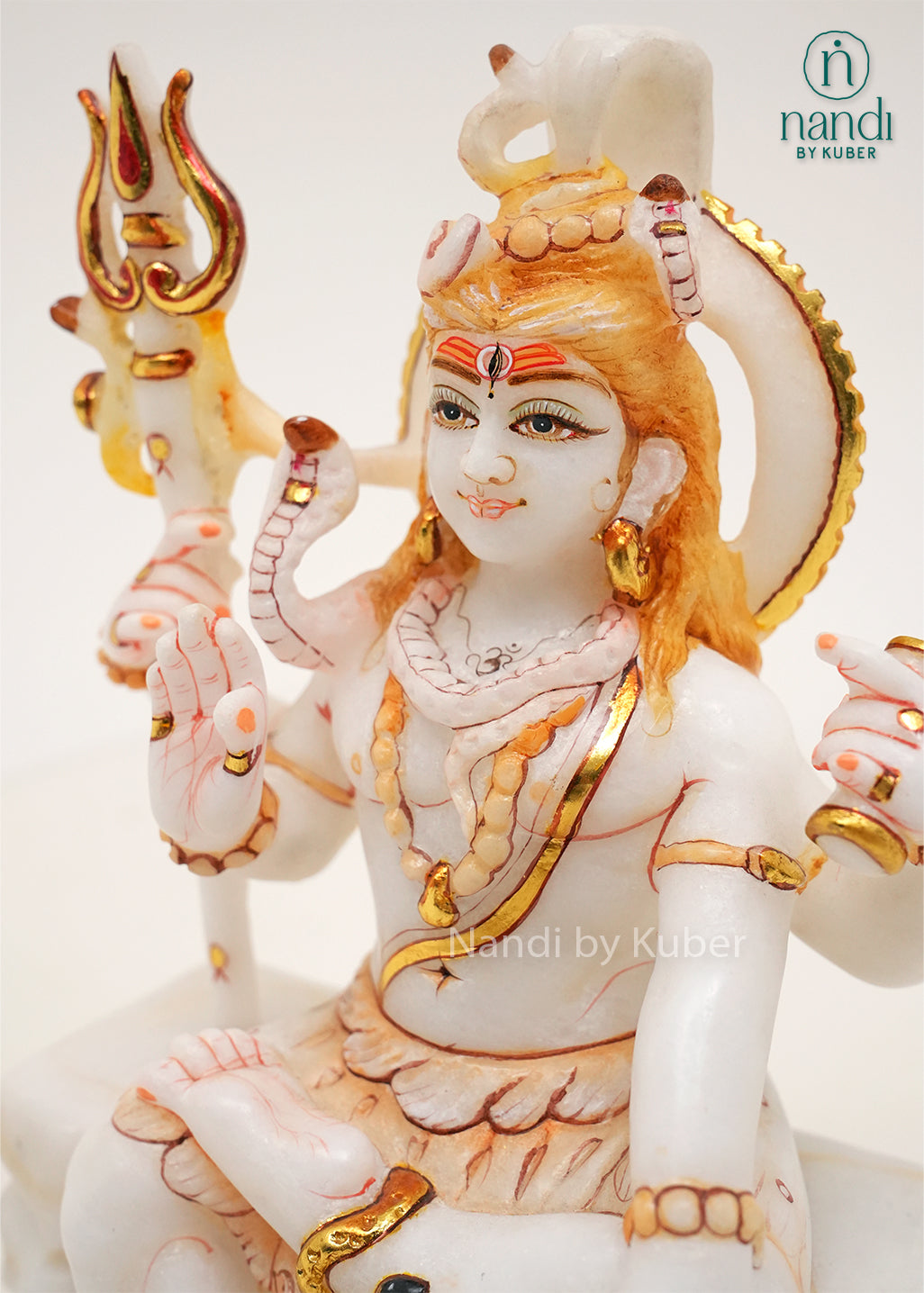 Handcrafted white marble Lord Shiva idol with gold accents, trident, Nandi bull, and traditional Hindu symbolism, ideal for home temples, spiritual décor, and religious gifting.