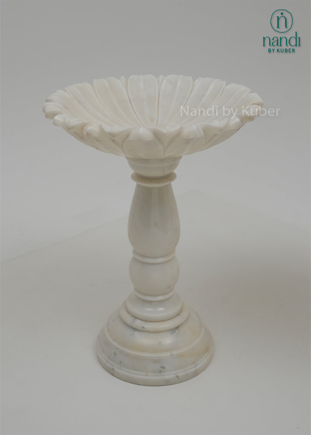 Set of two white marble urli bowls with pedestal stands and floral edges, decorative centerpiece bowls for home décor, festive decoration, weddings, and pooja arrangements.