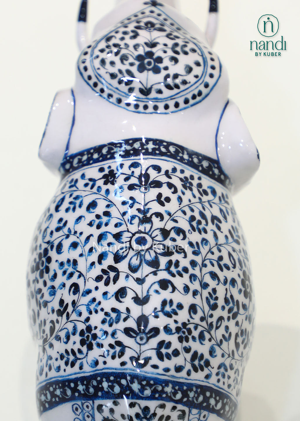 Handcrafted decorative elephant statue with raised trunk, white enamel finish and blue floral artwork, metal elephant figurine for home décor, office décor, and gifting.