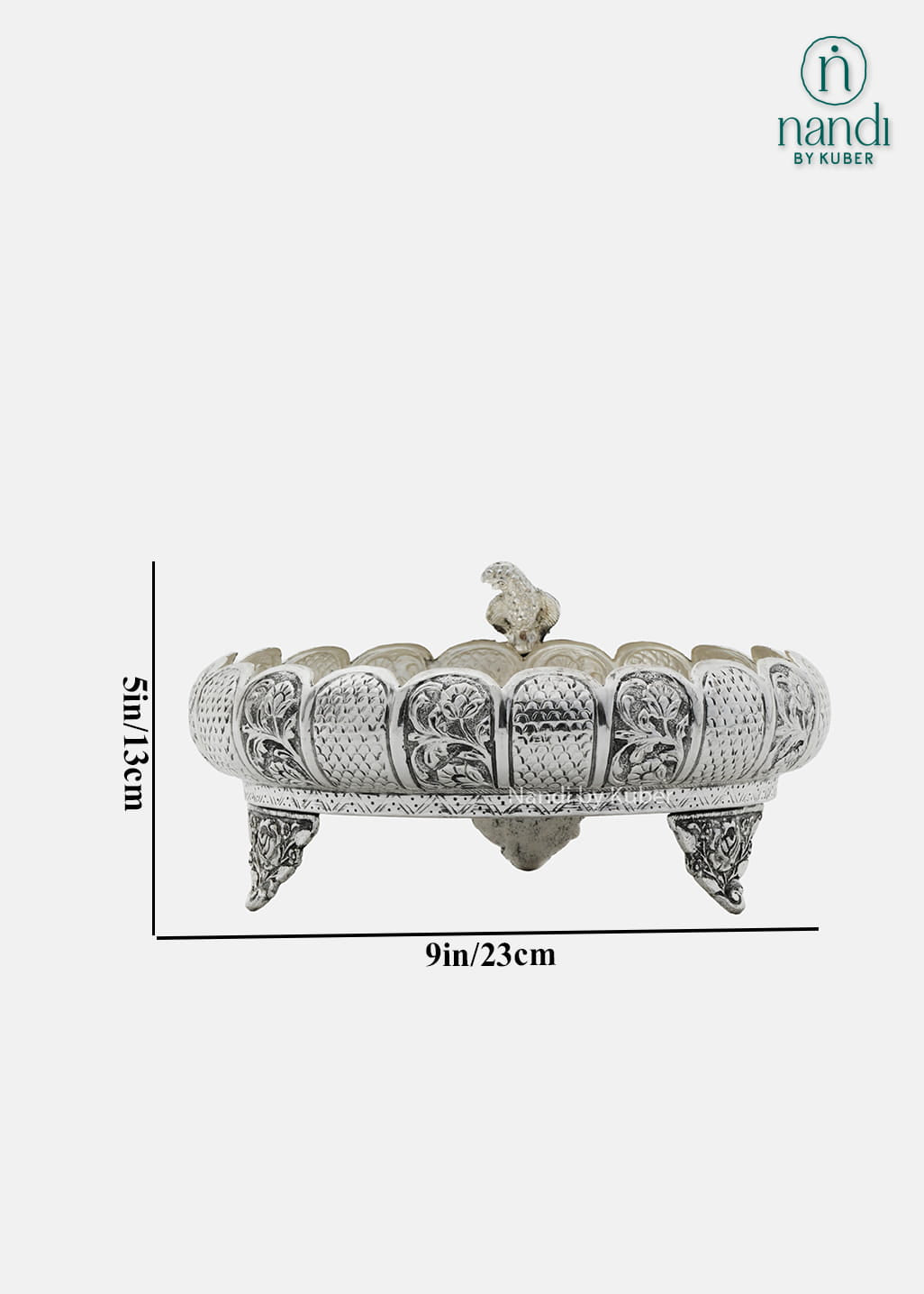Decorative silver metal urli bowl with intricate floral carvings and stand