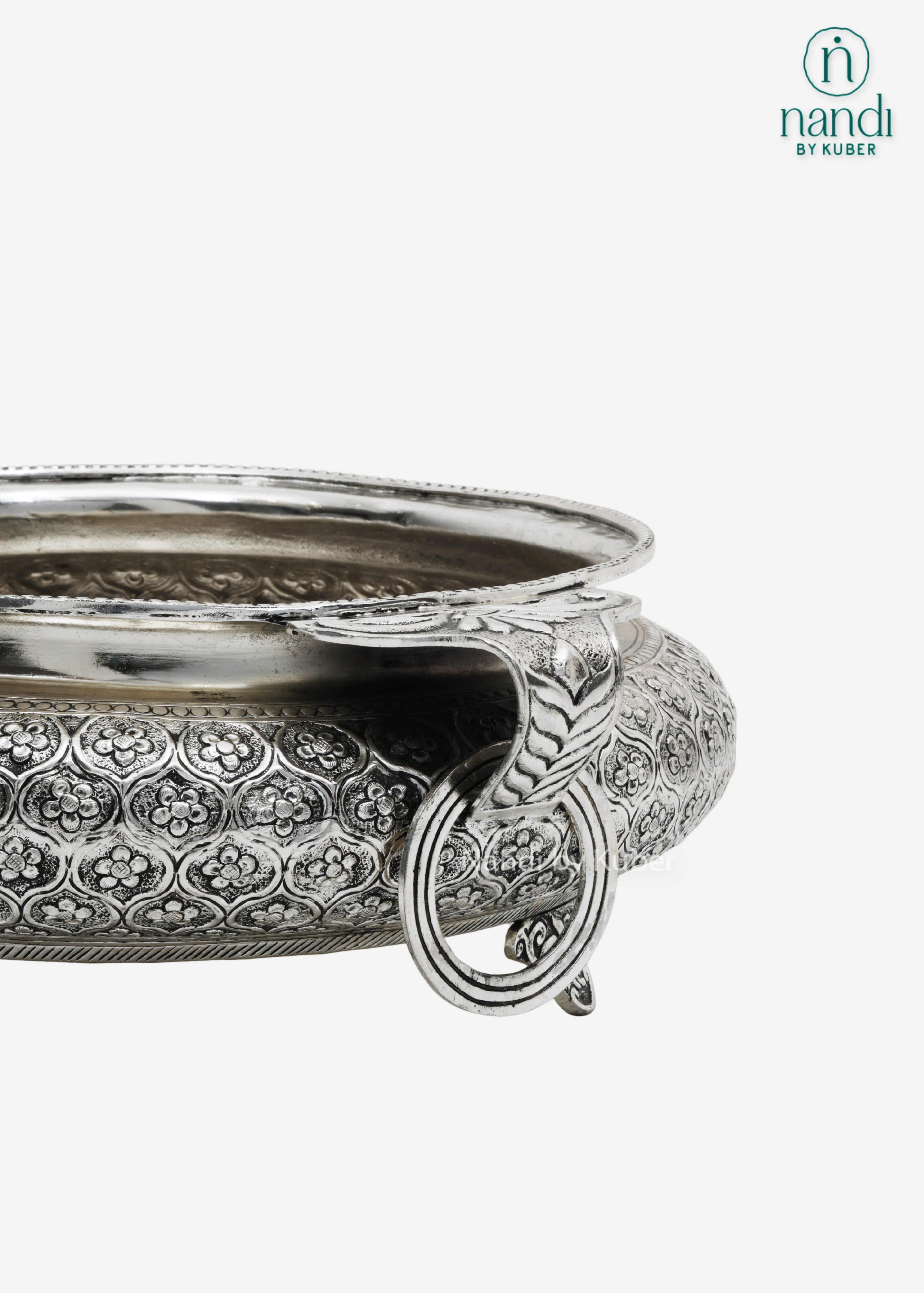 Decorative silver metal serving bowl with handles and intricate floral carving