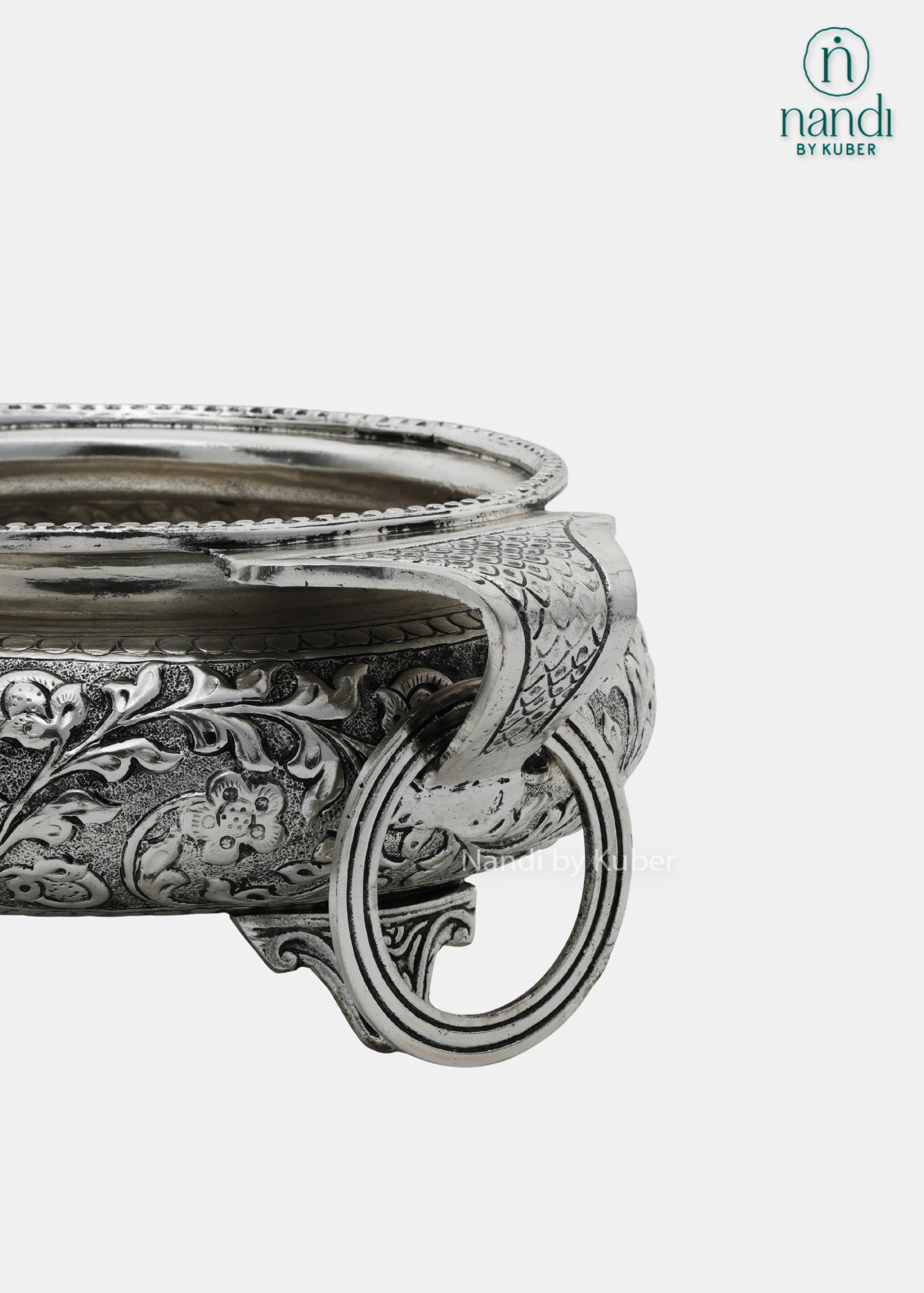 Decorative silver metal serving bowl with handles and intricate floral carving