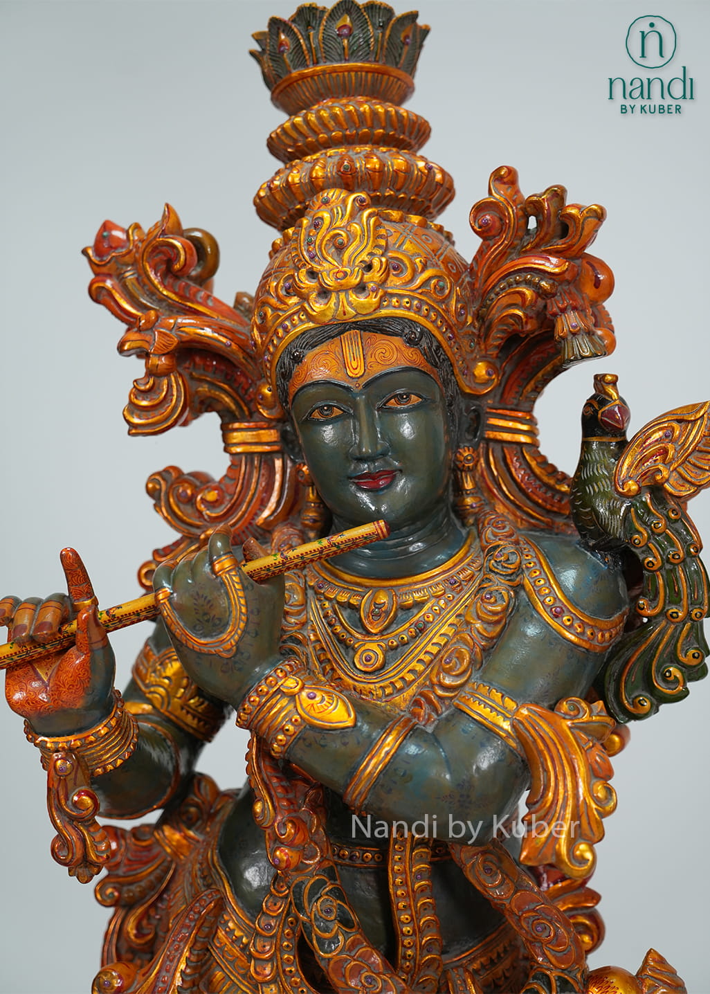 Decorative wooden Lord Krishna statue playing the flute, framed by two intricately carved tusk-style arches with detailed craftsmanship