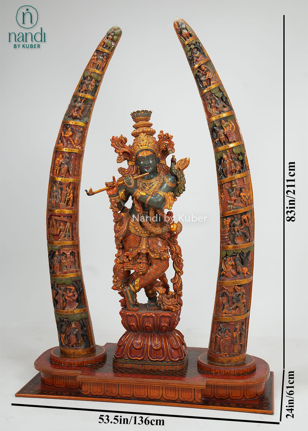 Decorative wooden Lord Krishna statue playing the flute, framed by two intricately carved tusk-style arches with detailed craftsmanship