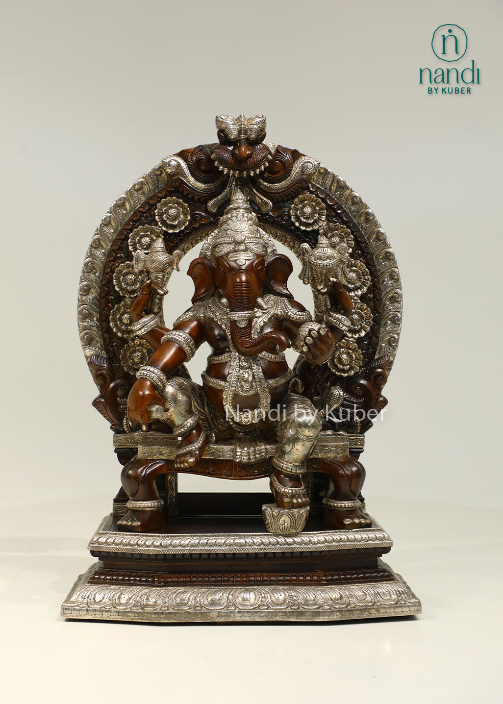 Handcrafted Lord Ganesha statue seated on an ornate royal throne with elegant silver detailing, perfect for devotional décor and spiritual spaces.