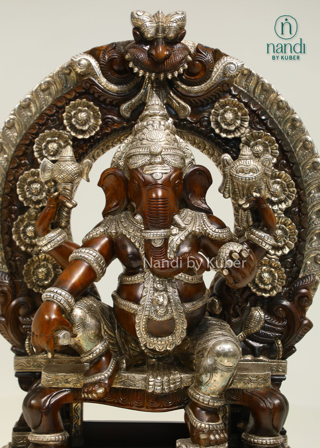 Handcrafted Lord Ganesha statue seated on an ornate royal throne with elegant silver detailing, perfect for devotional décor and spiritual spaces.