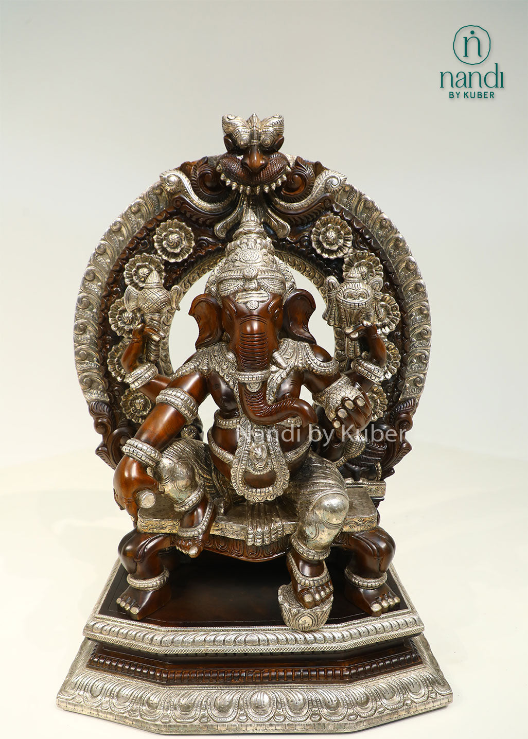 Handcrafted Lord Ganesha statue seated on an ornate royal throne with elegant silver detailing, perfect for devotional décor and spiritual spaces.